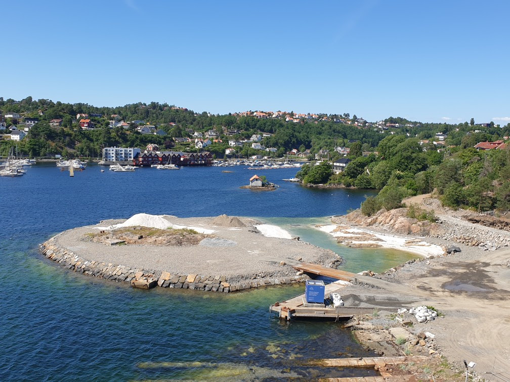 Slik ser det ut på Løkholmen nå. Til høyre i bildet ligger kanalen, med hvite sandstrender på begge sider. Sikringsarbeidet av fjellet bak pågår.
